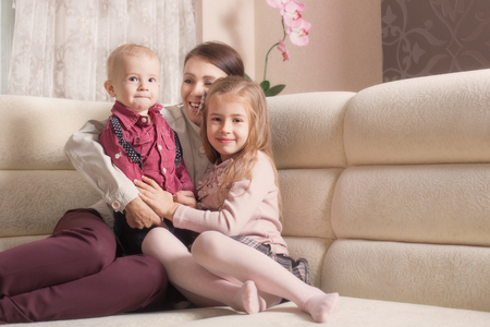 Mother sitting with her children on sofa at homeの写真素材