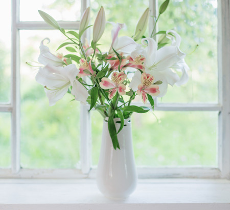 beautiful white lily in vase on windowsillの写真素材