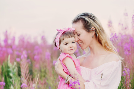 mother and her daughter outdoor in pink flowersの写真素材