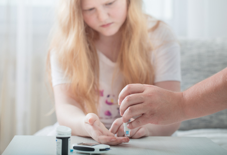 Measuring Blood Sugar Level Of Teen Girl With Glucometerの写真素材