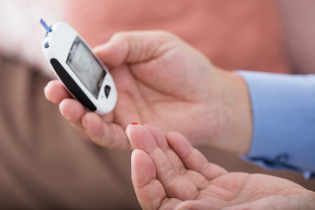 medicine, diabetes, glycemia, health care and people concept - close up of male finger with test stripeの写真素材