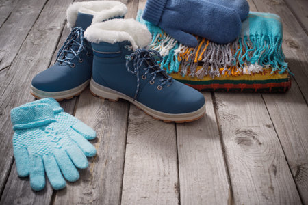Winter shoes, gloves, scarves  on old wooden backgroundの写真素材