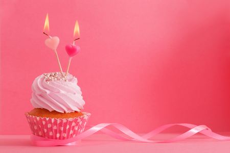 cupcake with candle on pink backgroundの写真素材