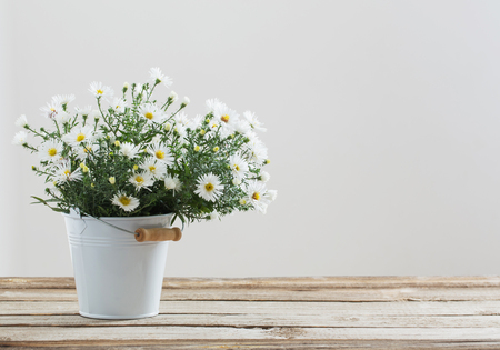 white flowers on bucket on wooden tableの写真素材