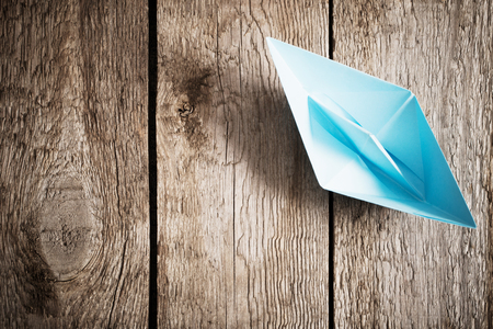 blue paper boat on old wooden backgroundの写真素材