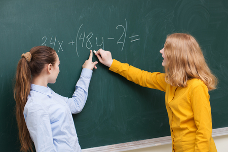 Two girls at the blackboard in a mathematics classの写真素材