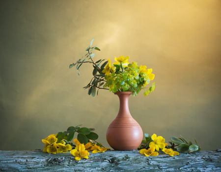 yellow flowers in vase on wooden tableの写真素材