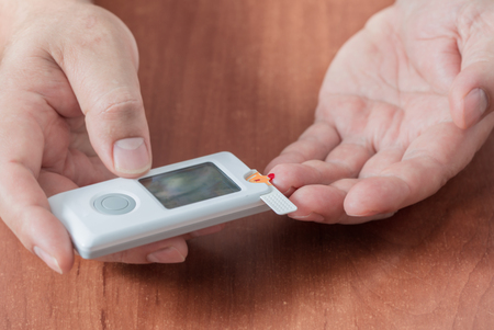 man measures sugar level with a glucometerの写真素材