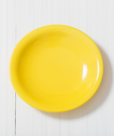 yellow plate on white wooden backgroundの写真素材