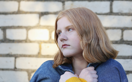 sad teenager girl on background brick wallの写真素材