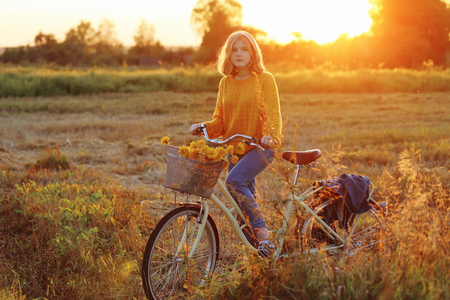 teenager girl on bike in summer field at sunsetの写真素材