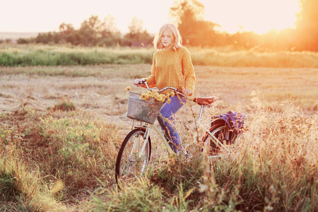 teenager girl on bike in summer field at sunsetの写真素材