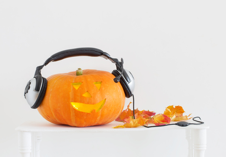 orange Halloween pumpkin with headphones on white backgroundの写真素材
