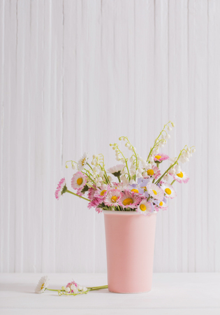 spring flowers in vase on white wooden backgroundの写真素材