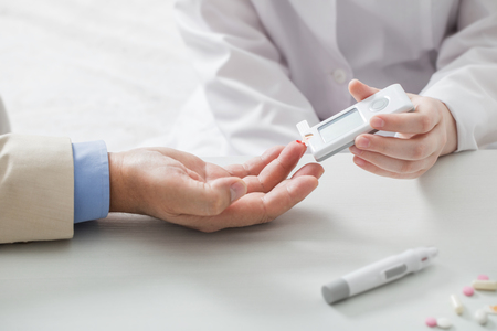 doctor measures the blood sugar level of the patientの写真素材