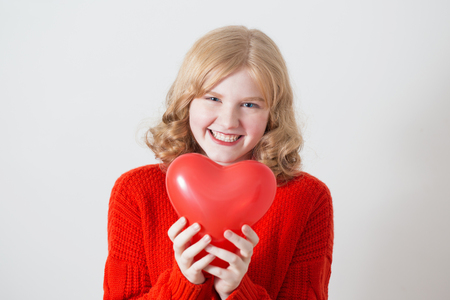 teen girl in red sweater with red balloons on white backgroundの写真素材