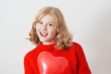 teen girl in red sweater with red balloons on white backgroundの写真素材