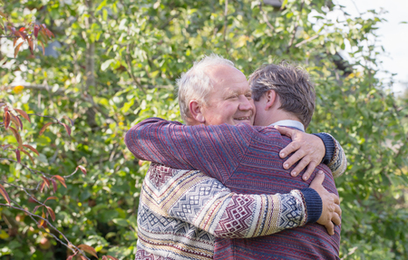two happy men hugging in autumn parkの写真素材