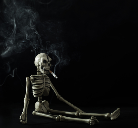 skeleton with a cigarette on a black backgroundの写真素材