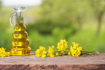 rapeseed oil (canola) and rape flowers on wooden tableの写真素材