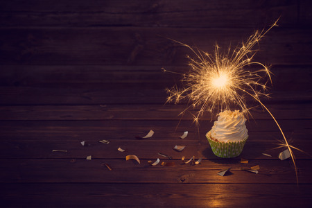 birthday cake with sparkler on old wooden backgroundの写真素材