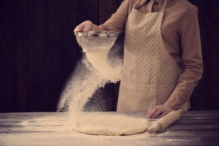 hands cooking dough on dark wooden background