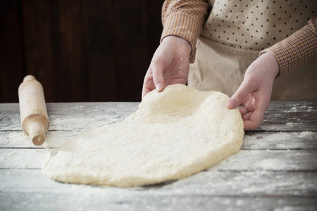 hands cooking dough on dark wooden background