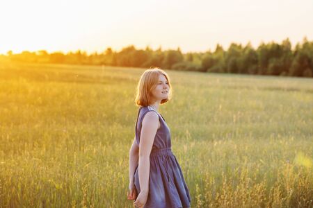 teenager girl in summer field at sunsetの写真素材