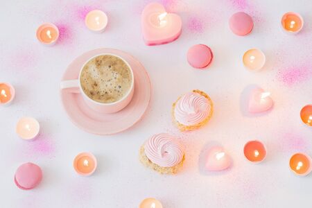 cup of coffee with burning candles on pink painted paper backgroundの写真素材
