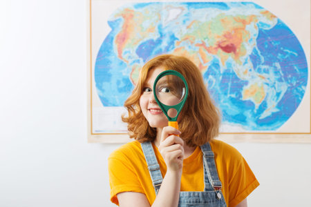 funny girl with magnifier stands at  geographical map