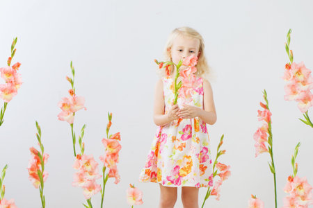 beautiful little blonde girls with gladiolus  flowers on white backgroundの写真素材