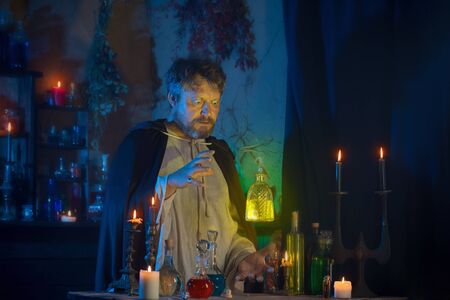 portrait of  wizard with burning candles and magic potionsの写真素材