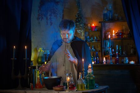 portrait of  wizard with burning candles and magic potionsの写真素材