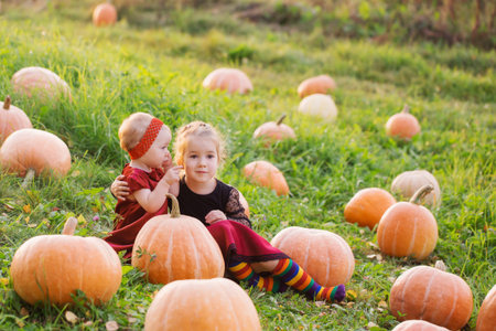 two little girls with orange pumpkins at sunset