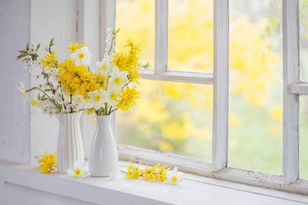 yellow spring flowers on old white windowsillの写真素材