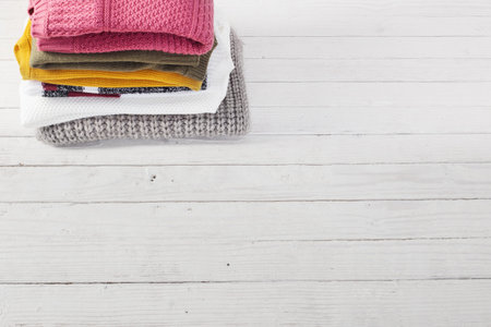 stack of sweaters on  white wooden table