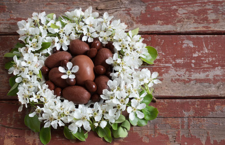 chocolate Easter eggs with spring flowers on wooden background