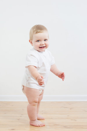 funny little  baby takes first steps on wooden floor