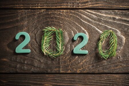 New Year composition, 2020 symbols and fir branches with cones on old wooden backgroundの写真素材