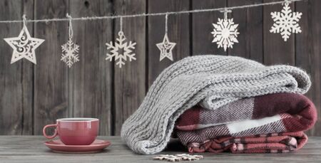 stack of plaids, cup of tea  and Christmas decorations on old wooden backgroundの写真素材