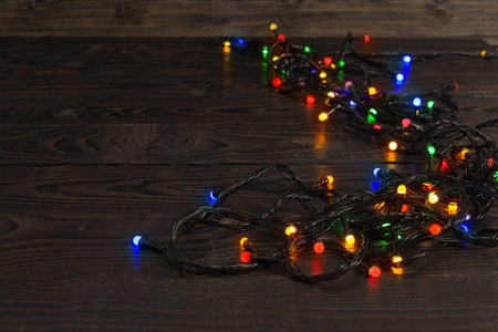electric garland with multi-colored light bulbs on a wooden surface, Christmas and New Year...