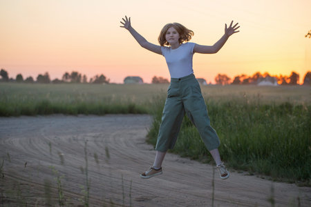 funny teenager girl jumping outdoor at sunset