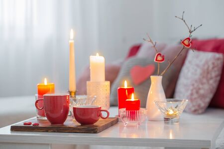 Burning candles on white table in interior. Valentines day conceptの写真素材