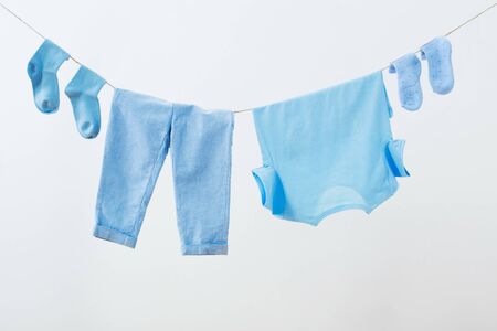 baby clothes hanging on  rope on white backgroundの写真素材