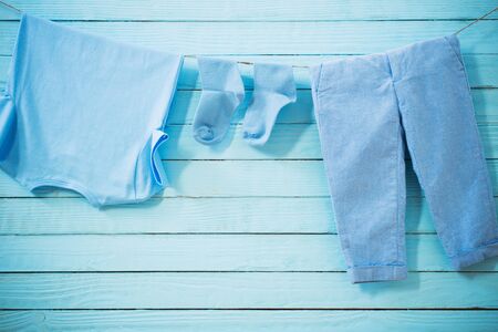 baby clothes hanging on  rope on wooden backgroundの写真素材