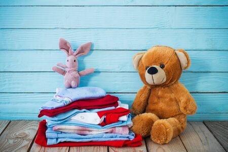 baby clothes and toy bear on old wooden backgroundの写真素材