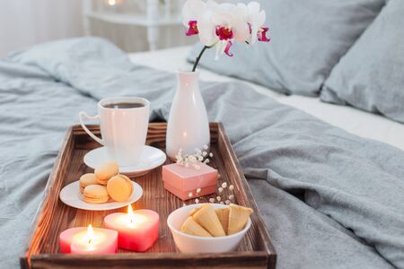 Coffee, sweets,  candles, flowers and girt on wooden tray on bed. Concept with Valentines dayの写真素材