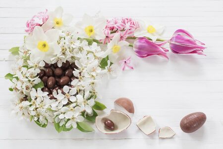 chocolate Easter eggs with spring flowers on wooden backgroundの写真素材
