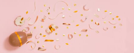 Easter chocolate egg with golden confetti on pink backgroundの写真素材