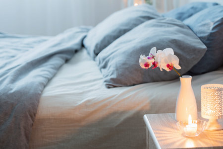 orched flowers  in vase and burning candles in white bedroom